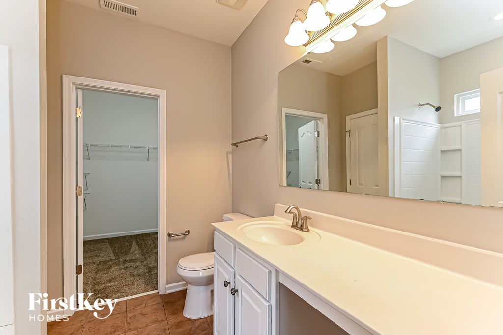 A bathroom with a sink, toilet, and mirror.