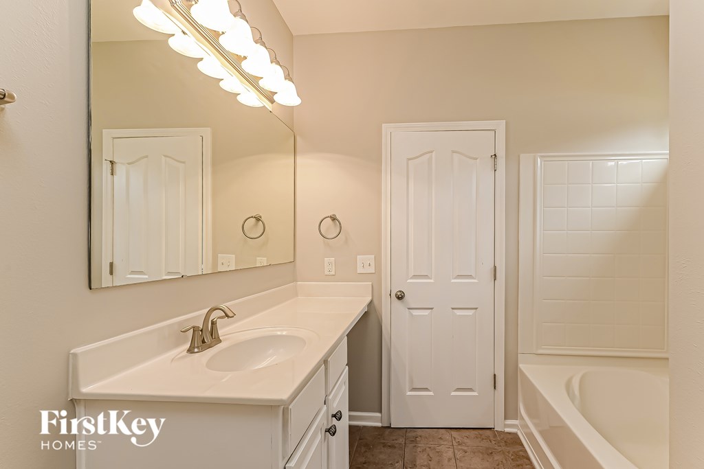 A bathroom with a sink, mirror, and tub.