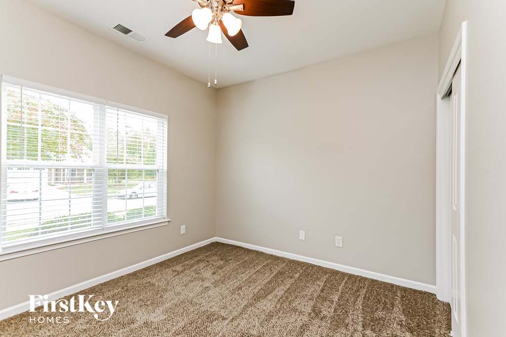 A room with a carpeted floor and a ceiling fan.