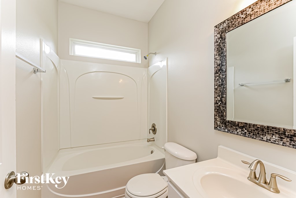 A white bathroom with a tub, toilet and sink.