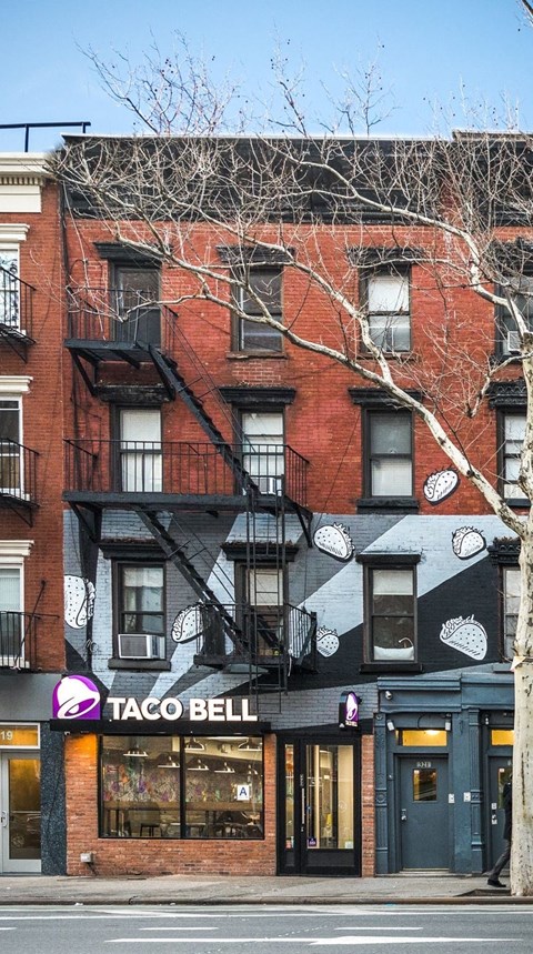 A Taco Bell restaurant is located in a brick building with a black and white awning.