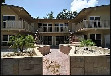 an apartment building with palm trees in front of it