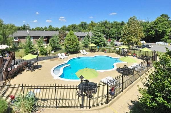 A black fence surrounds a small pool with a kid playing in it.