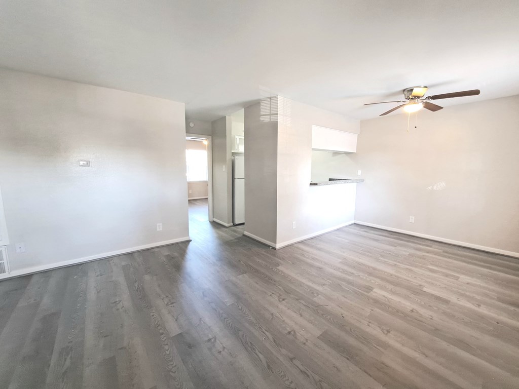 an empty living room with white walls and a ceiling fan