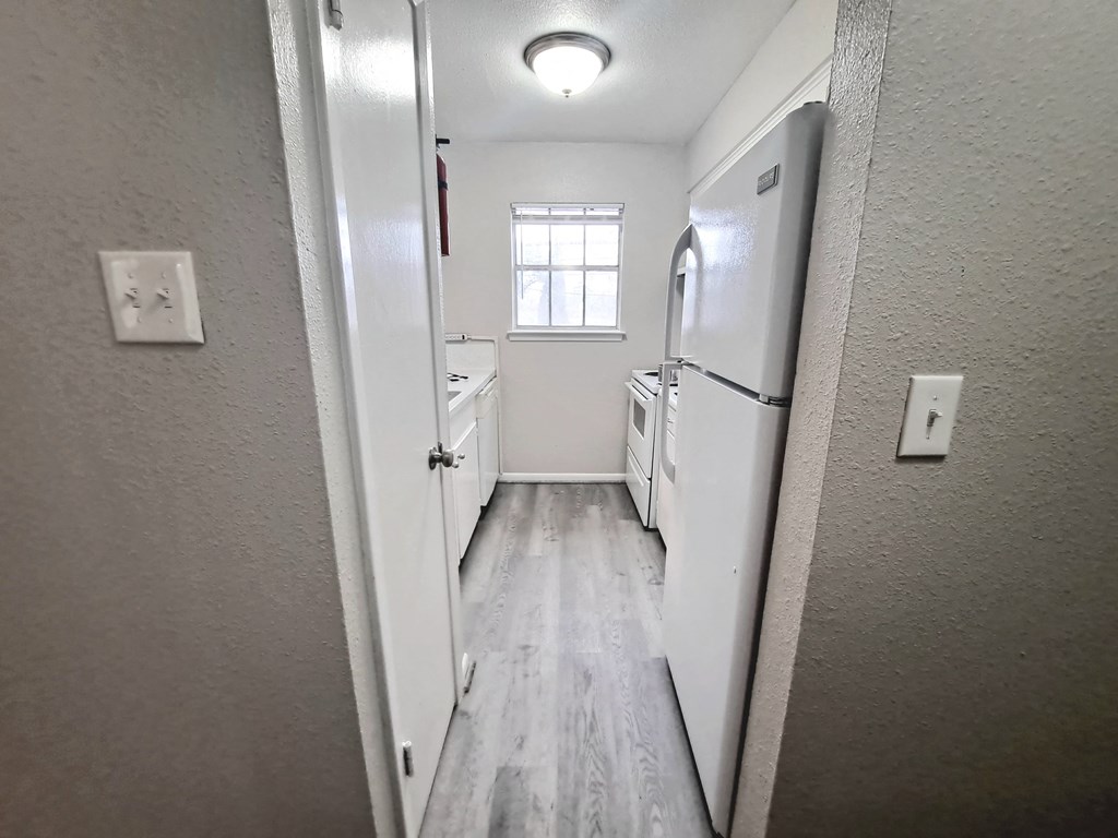 a long narrow kitchen with a refrigerator and a sink