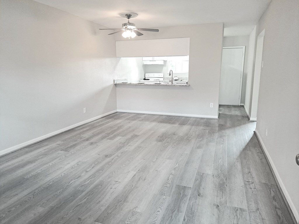 an empty living room with wood flooring and a ceiling fan