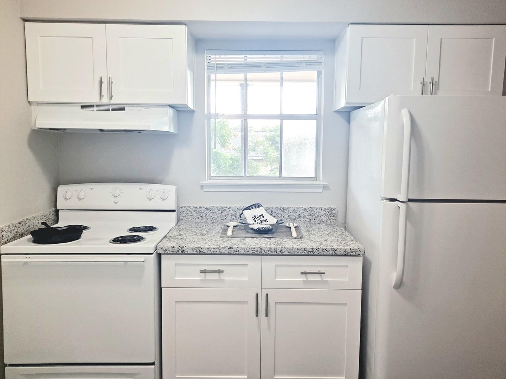 a white kitchen with white appliances and granite counter tops
