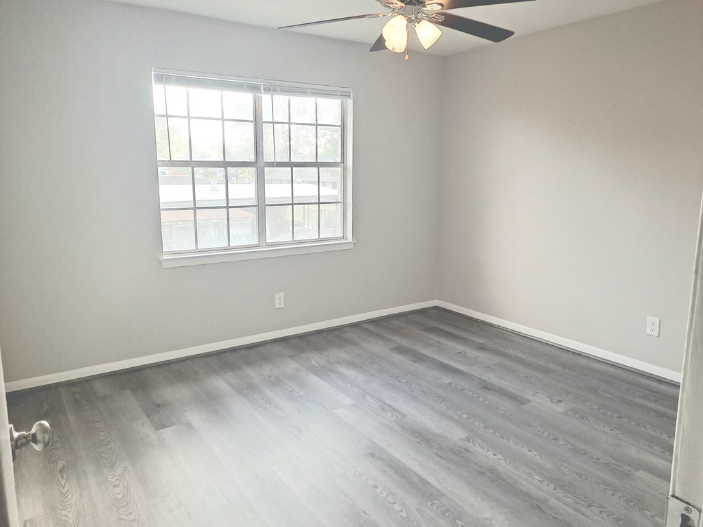 an empty bedroom with wood floors and a window