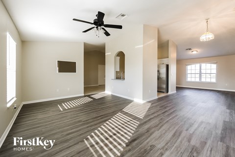 A spacious room with a ceiling fan and wooden flooring.