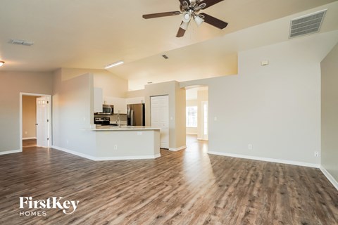A spacious living room with a ceiling fan and hardwood floors.