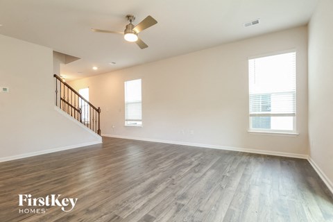 A spacious room with a wooden floor and a ceiling fan.