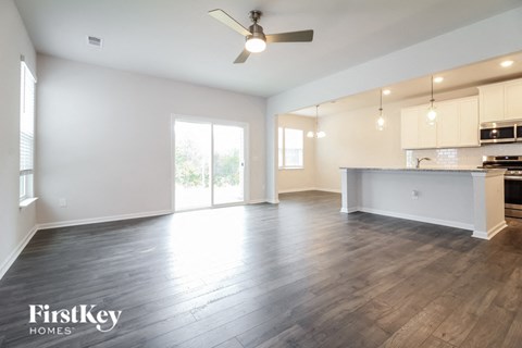 A spacious room with a kitchen area and a ceiling fan.