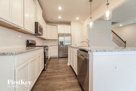 A kitchen with white cabinets and a stainless steel refrigerator.