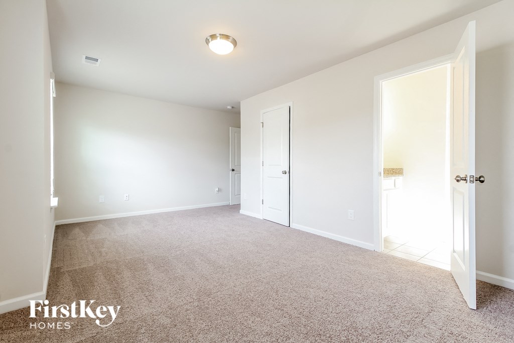 a bedroom with white walls and carpet and a door to a closet