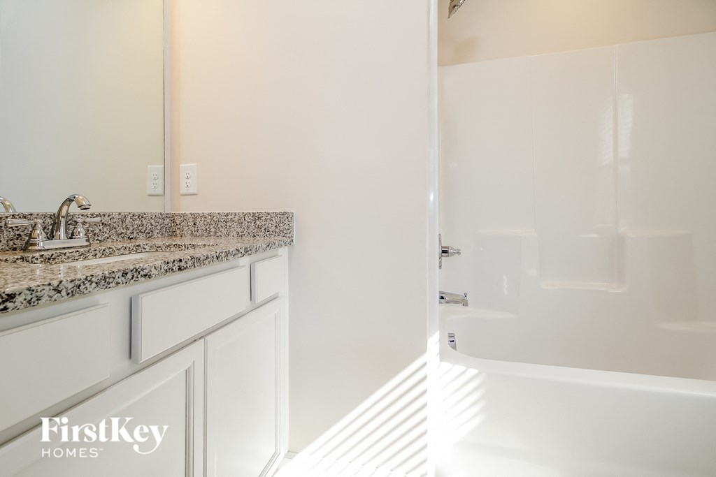 a bathroom with white cabinets and a sink and a shower