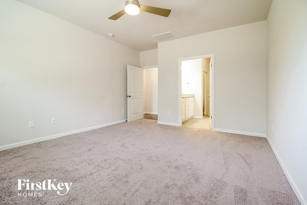 a spacious living room with carpet and a ceiling fan