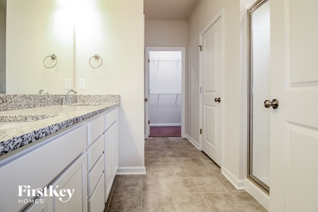 a bathroom with white cabinets and a sink and a shower