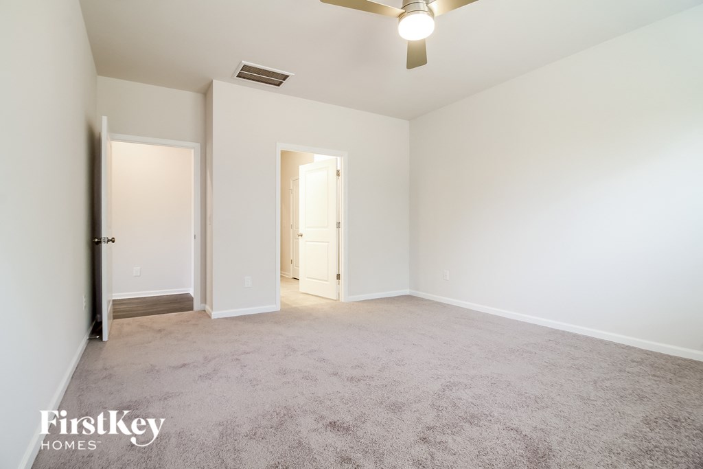 a spacious living room with carpet and a ceiling fan