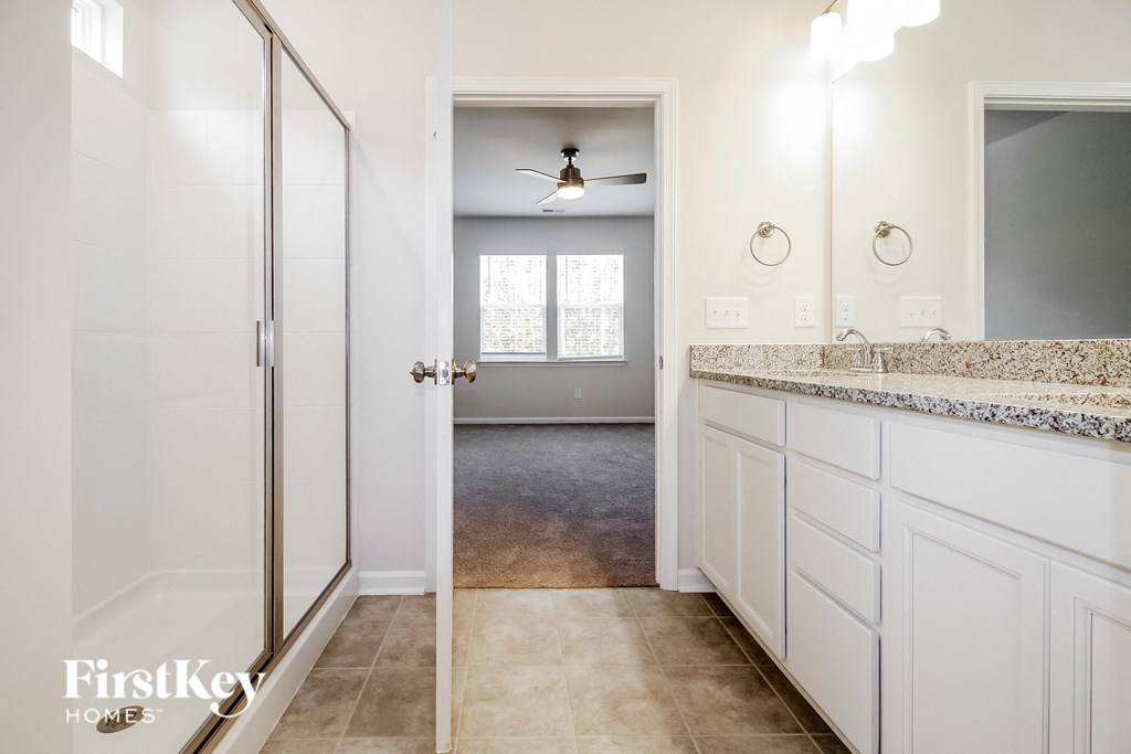 a bathroom with white cabinets and a sink and a shower
