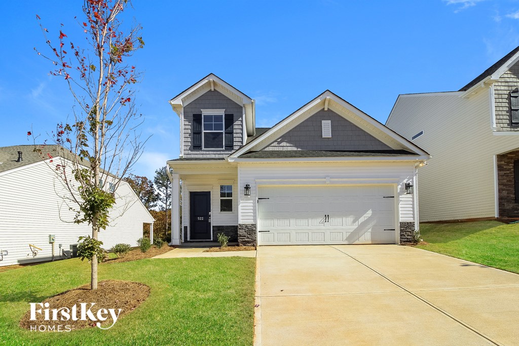 A house with a garage and a tree in front of it.