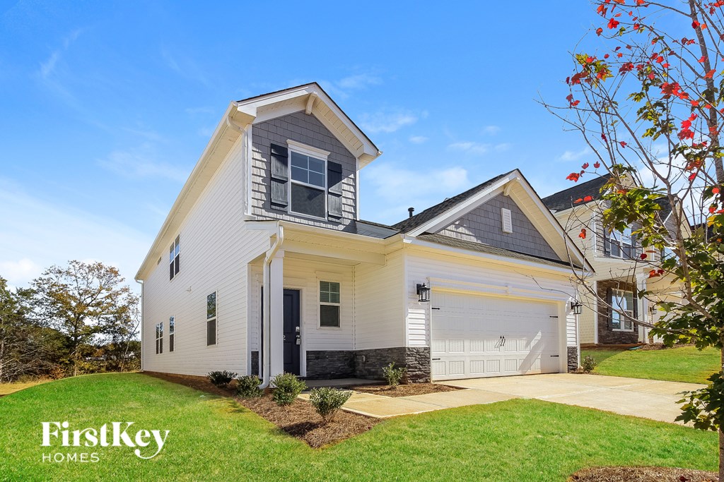 A house with a garage and a tree with red leaves in front of it.