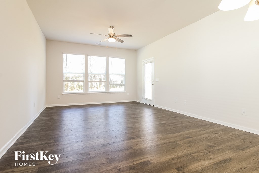 A spacious room with wooden floors and a ceiling fan.