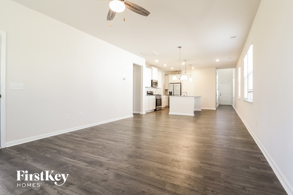 A spacious room with wooden floors and a kitchen area in the background.