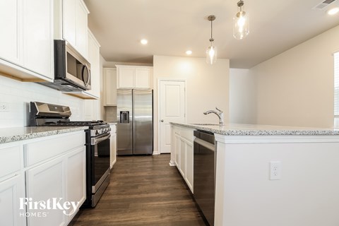 A kitchen with white cabinets and a granite countertop.
