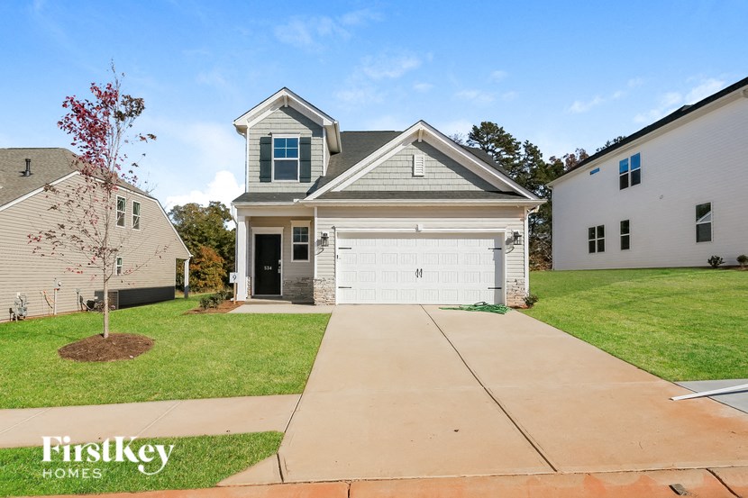 A house with a grey roof and a white garage door is for sale.