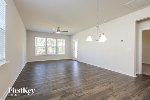 A spacious room with wooden floors and a ceiling fan.