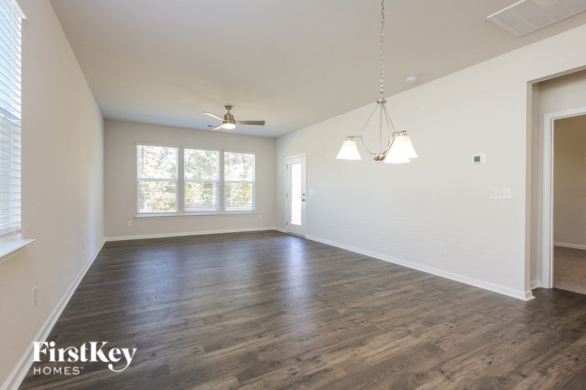 A spacious room with wooden floors and a ceiling fan.