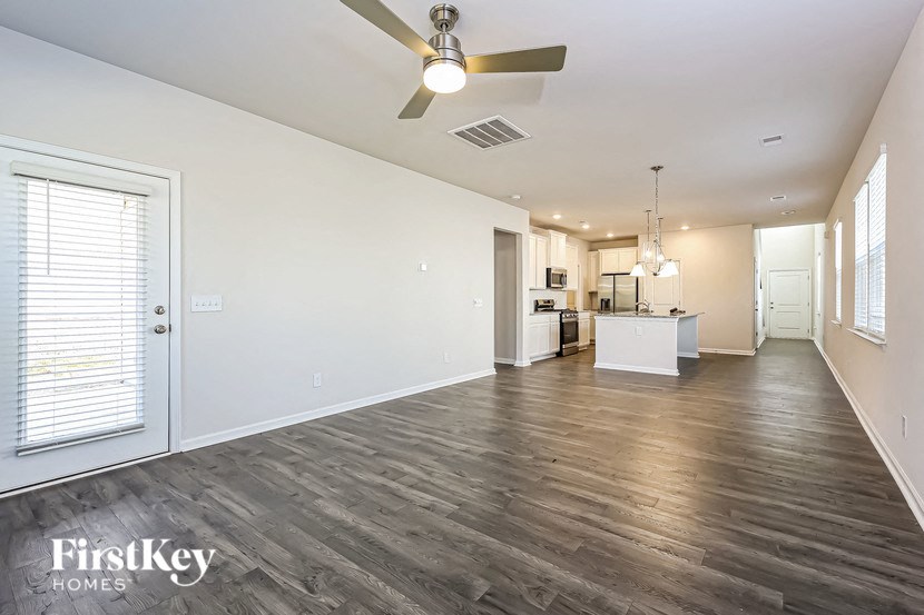 an empty living room with a ceiling fan and a kitchen