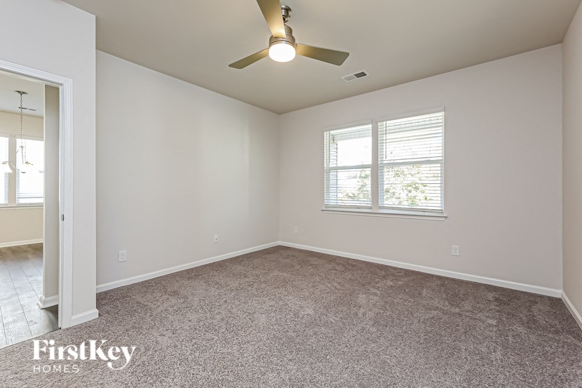 an empty living room with a ceiling fan and a window