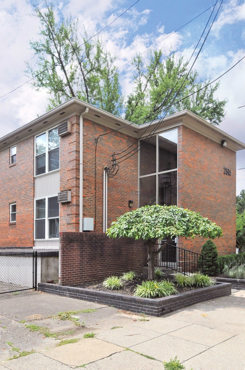 A red brick house with a tree in front.