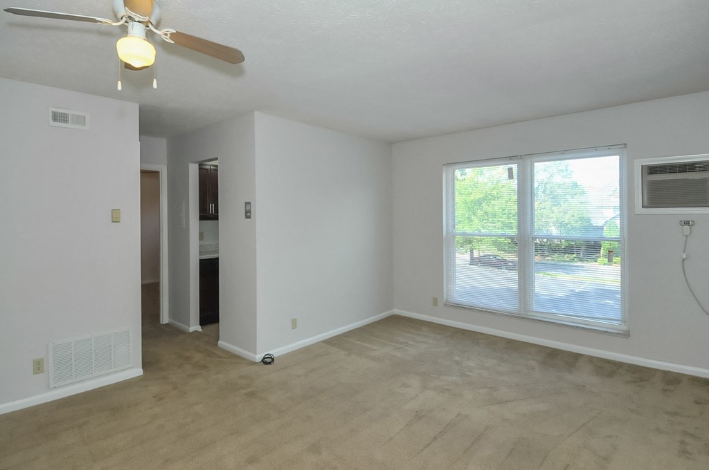 A room with a ceiling fan and a window overlooking a street.