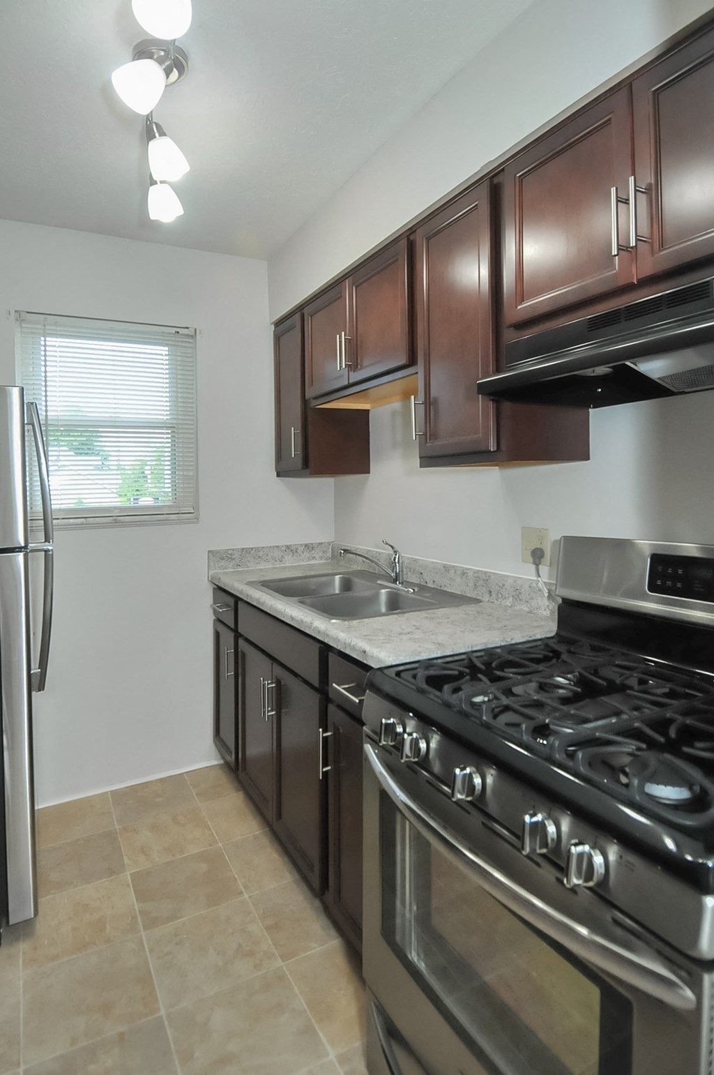 A kitchen with a stove, sink, and refrigerator.