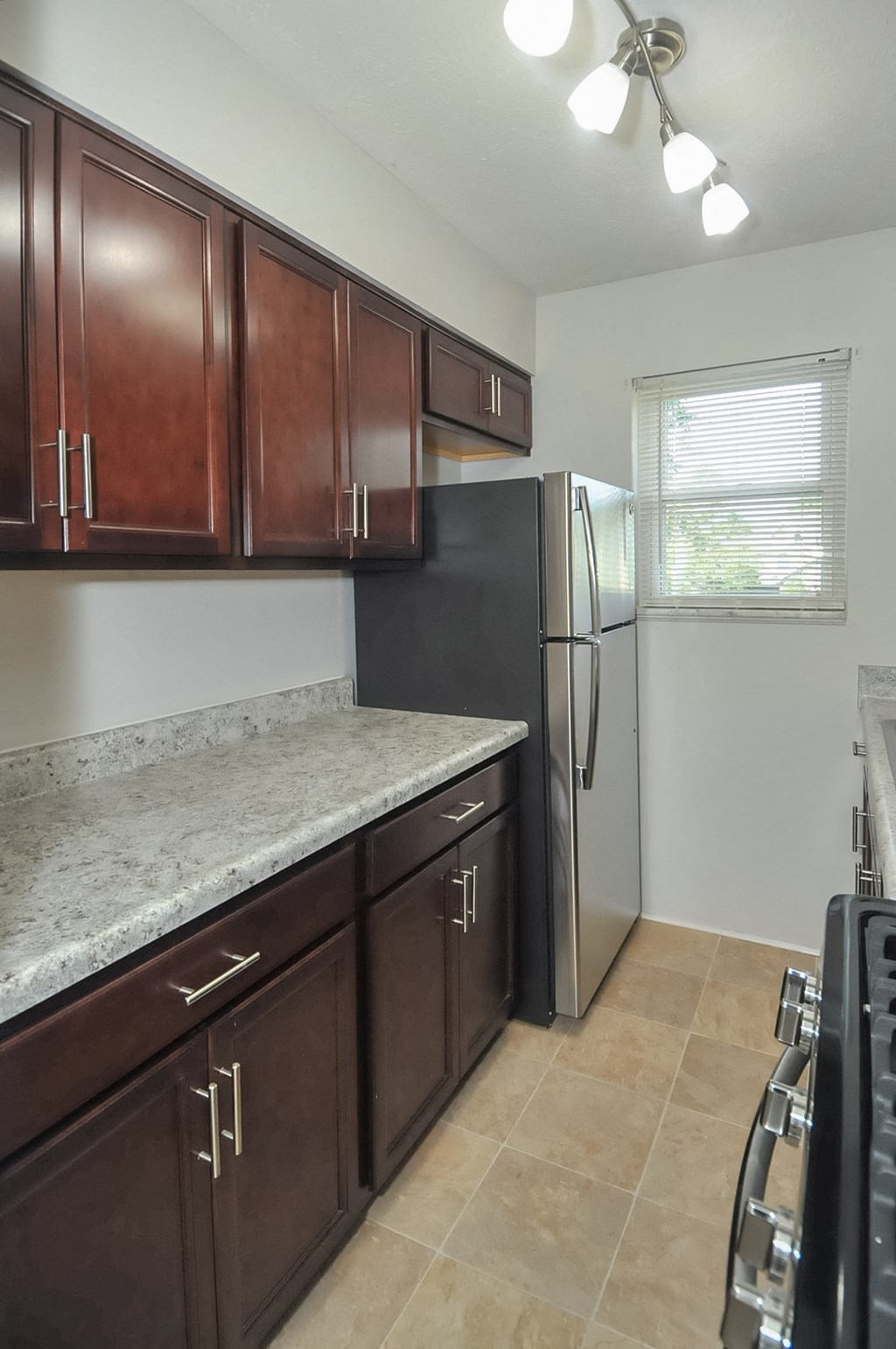 A kitchen with brown cabinets and a black refrigerator.