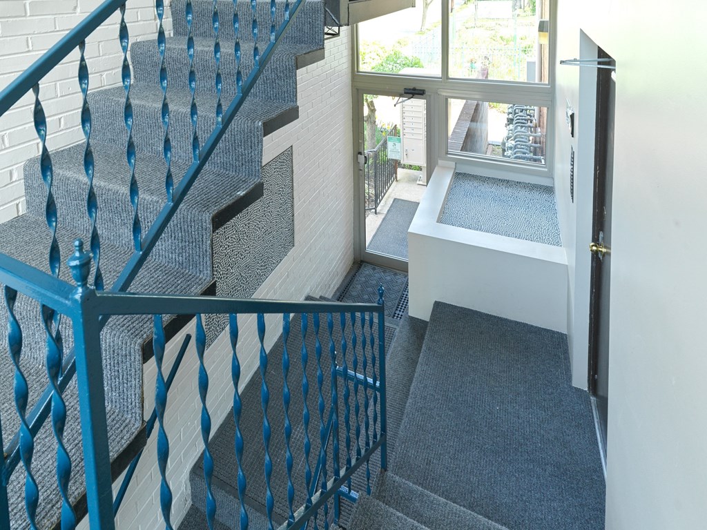 A staircase with a blue railing and a grey carpet.
