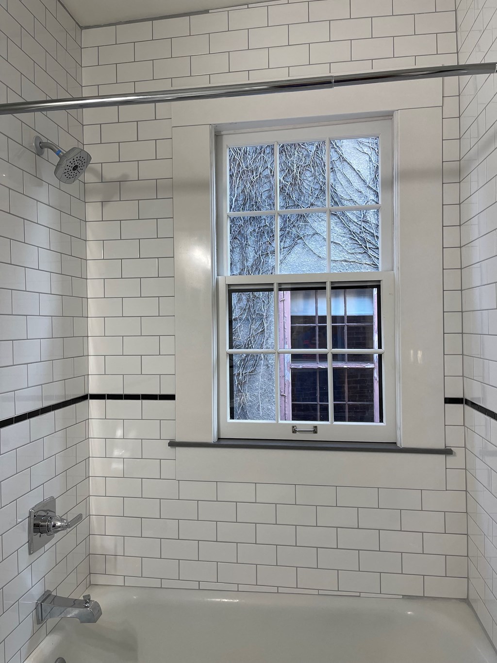 A white tiled bathroom with a window.