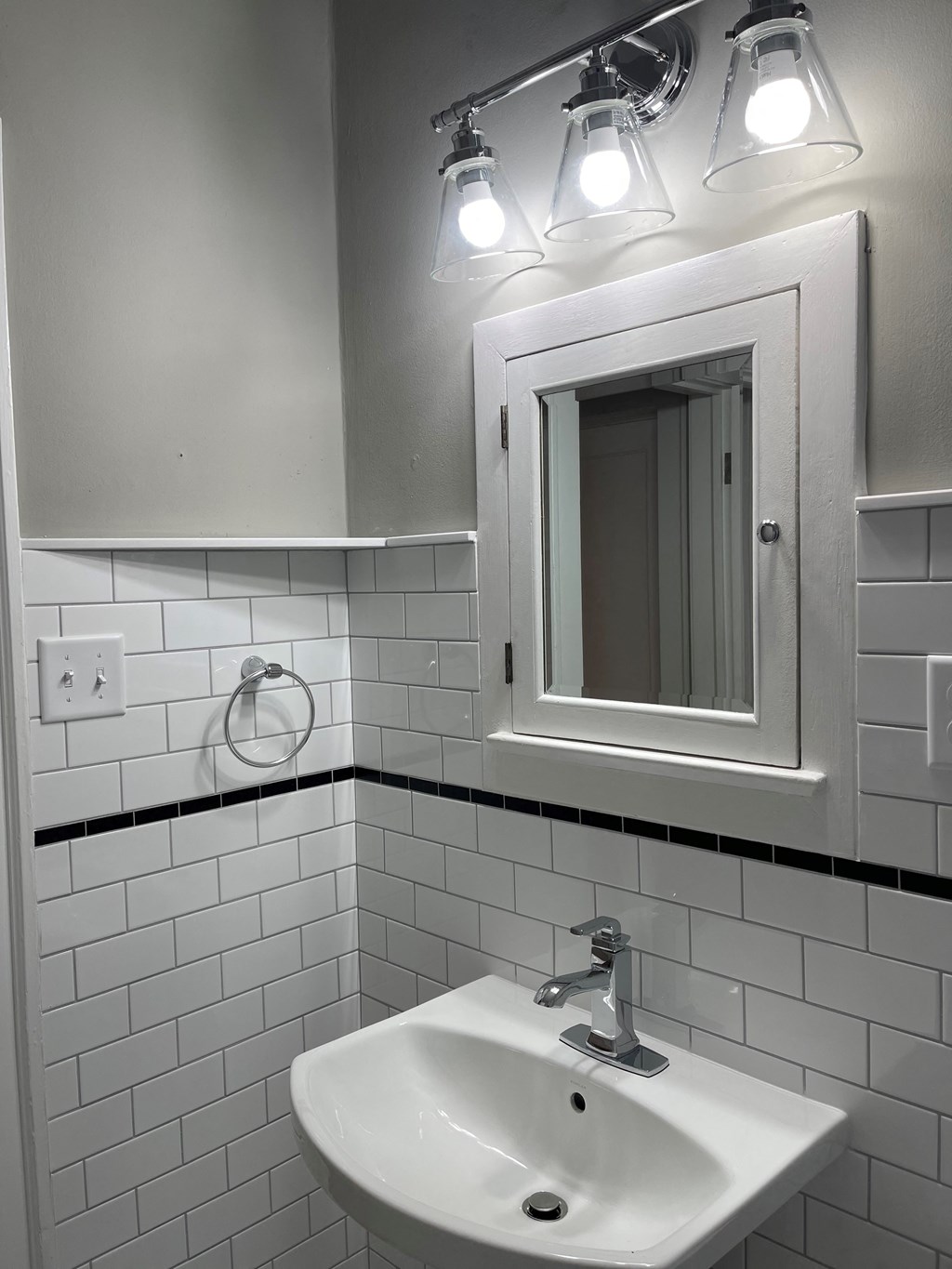 A white sink in a bathroom with a mirror above it.