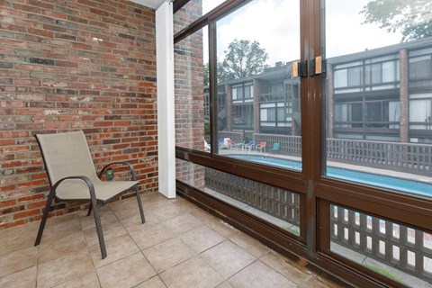 A chair is placed on a balcony with a glass door.