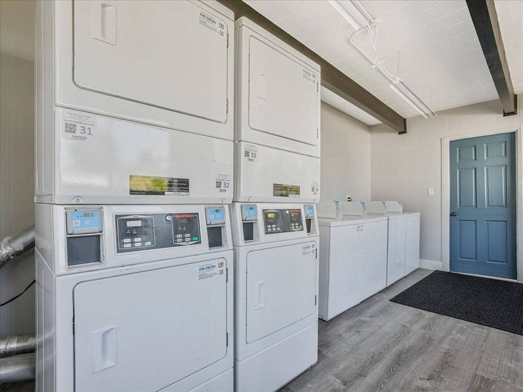 a row of white washers and dryers in a room with a blue door