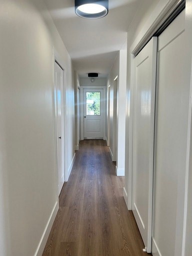 A long hallway with white walls and wood floors.