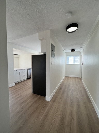 an empty living room and kitchen with wood floors