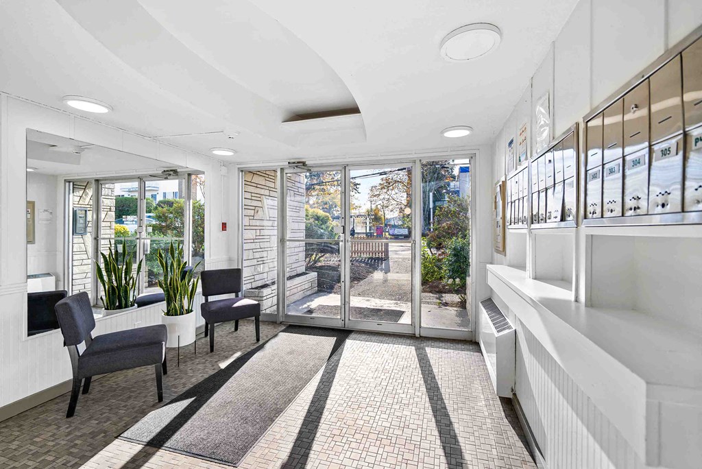 a lobby with chairs and a table and glass doors
