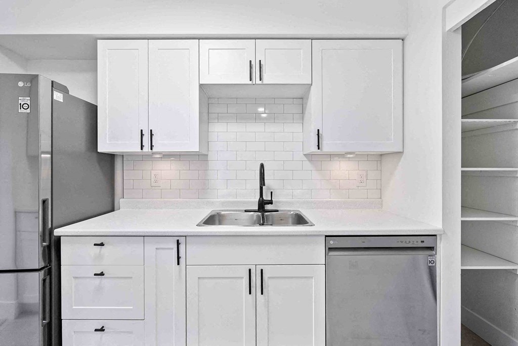 a kitchen with white cabinets and a sink and a refrigerator
