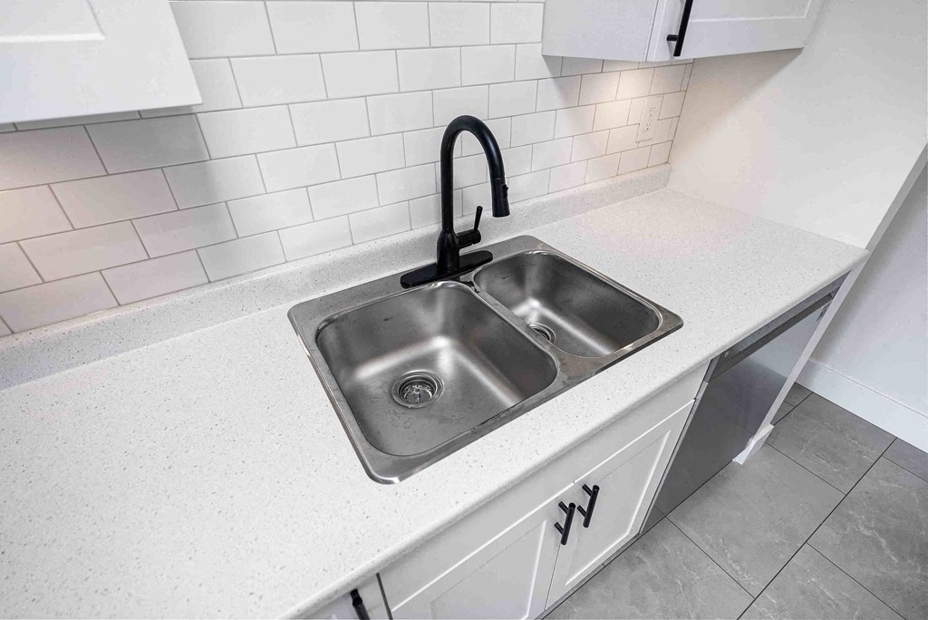 a stainless steel sink in a kitchen with white counter tops