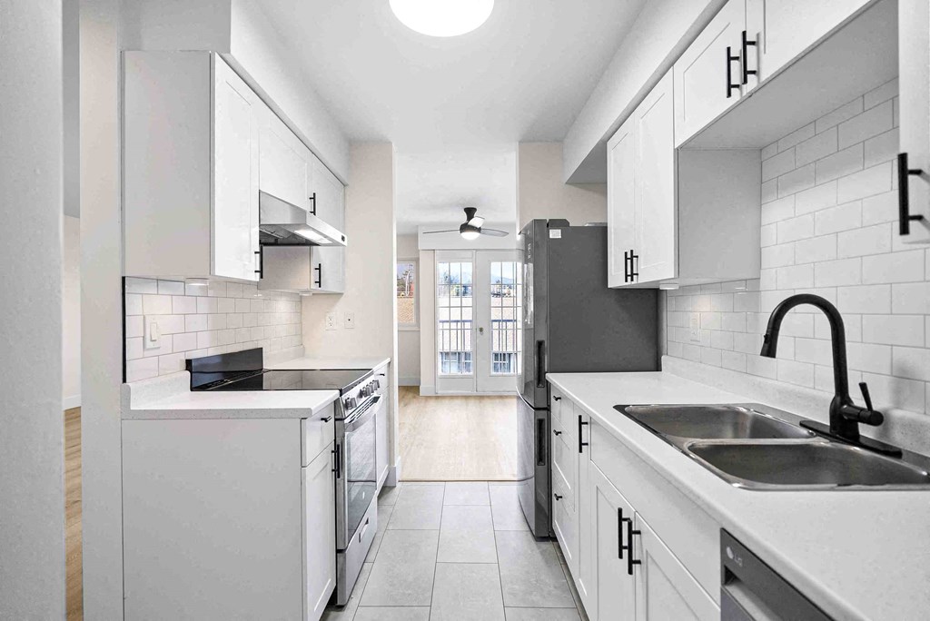 a kitchen with white cabinets and a sink and a stove