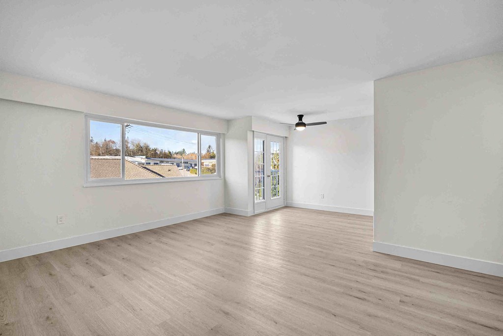 an empty living room with white walls and a window
