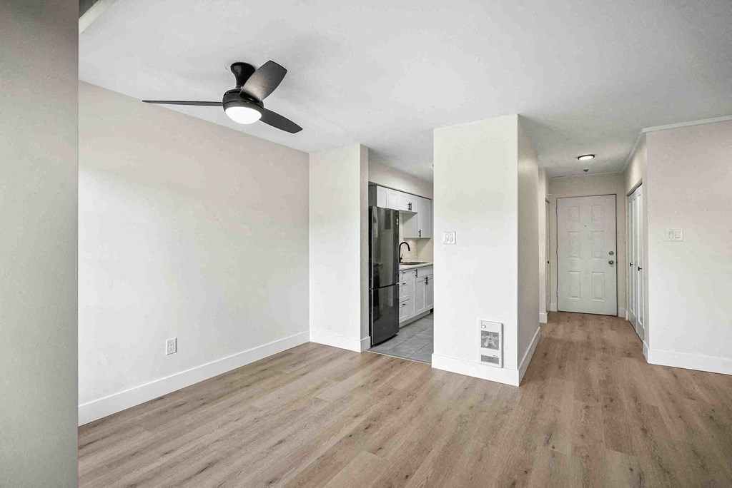 an empty living room with white walls and a ceiling fan